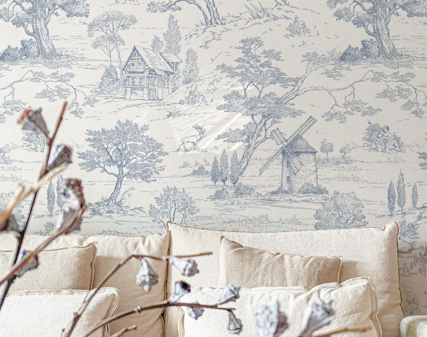 Wallpaper with a pastoral (Toile de Jouy) scene featuring trees and a windmill in a room with beige furniture.