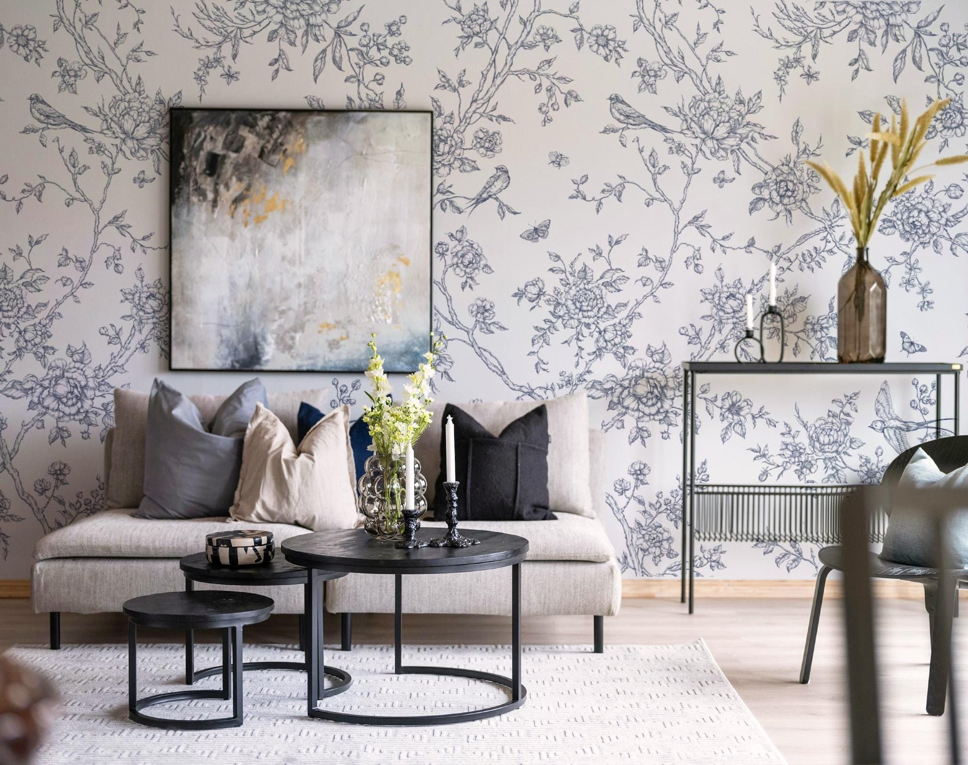 Living room with Toile de Jouy Floral Poetry wallpaper, gray sofa, and decorative elements.