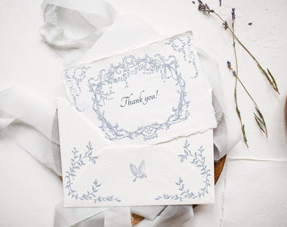 Wedding invitation suite featuring Ornella Blue oval crest and floral border