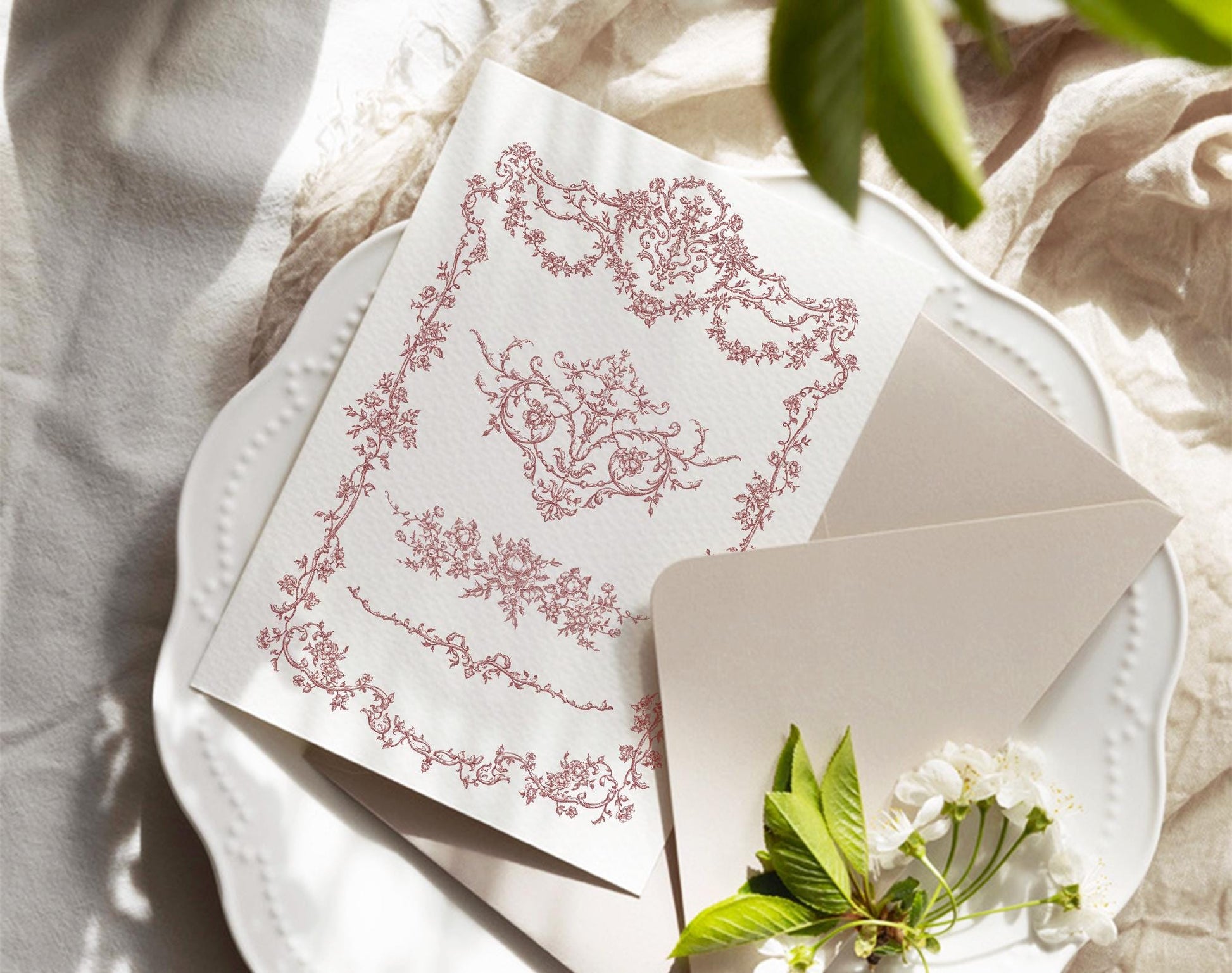 Burgundy floral frame design printed on a card beside an envelope and white flowers.