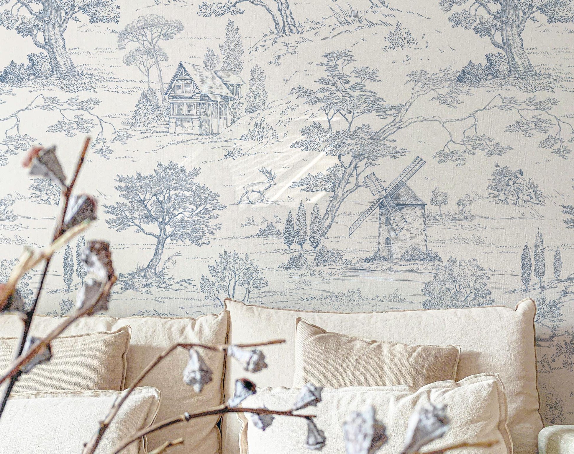 Wallpaper with a pastoral (Toile de Jouy) scene featuring trees and a windmill in a room with beige furniture.
