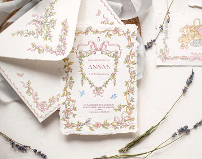 Little Bear Girl floral frame artwork shown on a printed birthday invitation beside a matching envelope and lavender sprigs.