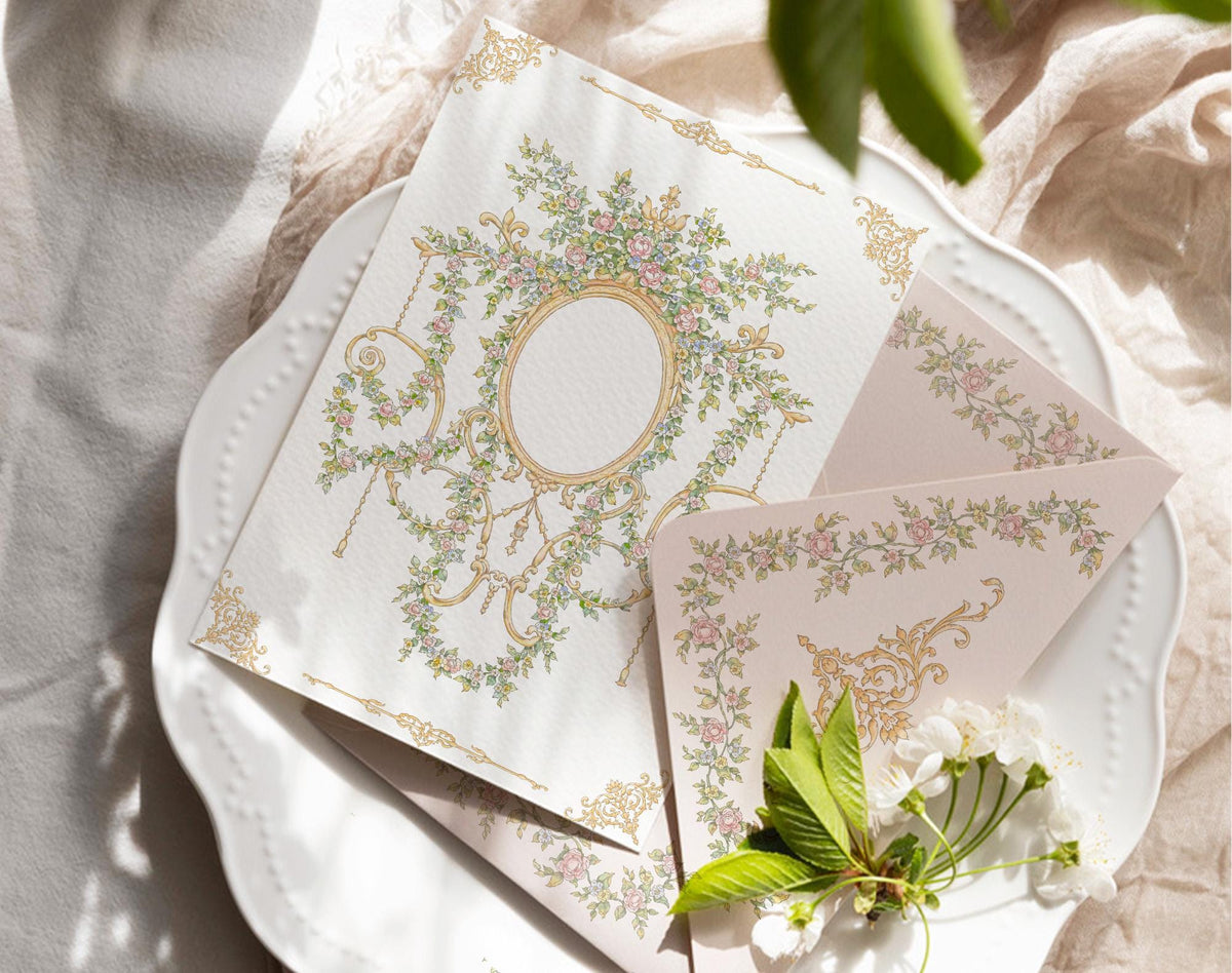 Vintage floral crest and rose border artwork displayed on a printed invitation card and matching envelope.